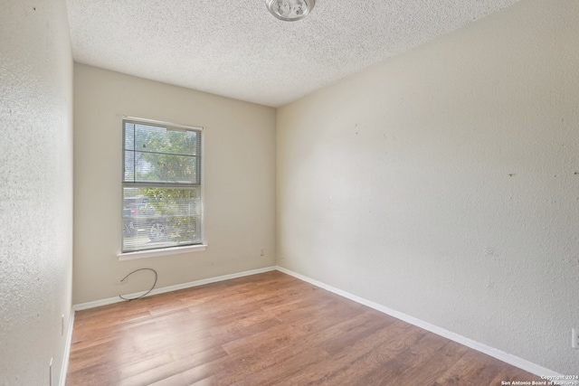 spare room with light hardwood / wood-style flooring and a textured ceiling