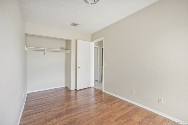 unfurnished bedroom featuring a textured ceiling, a closet, and dark hardwood / wood-style flooring