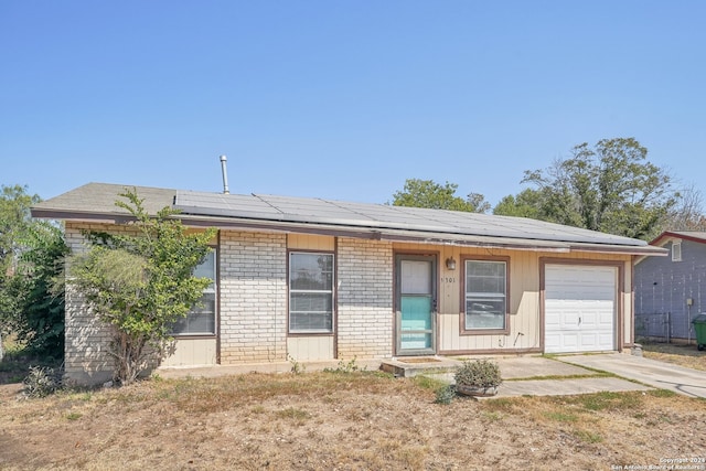 ranch-style home featuring solar panels and a garage