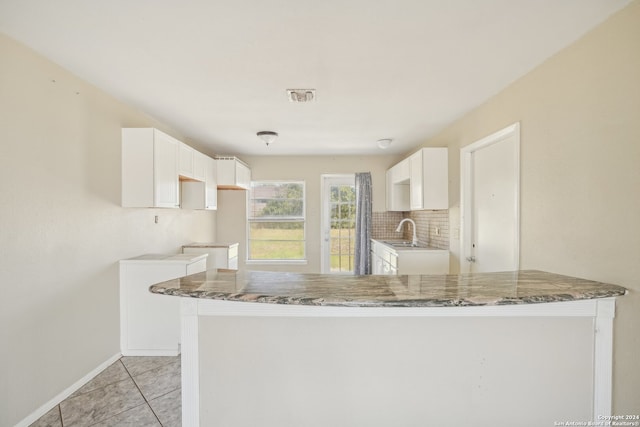 kitchen featuring sink, white cabinets, kitchen peninsula, and backsplash