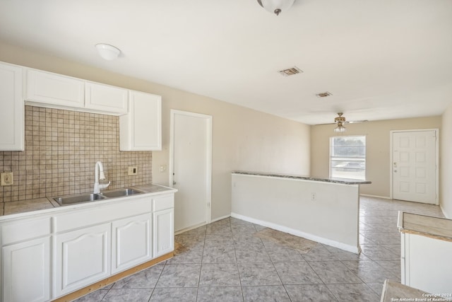 kitchen with light tile patterned floors, tasteful backsplash, sink, and white cabinets