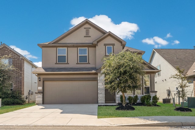 view of front of home featuring a front lawn, central AC unit, and a garage