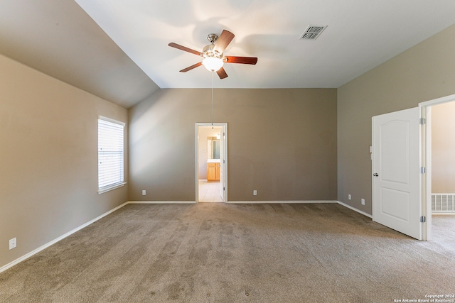 empty room featuring light carpet, ceiling fan, and vaulted ceiling