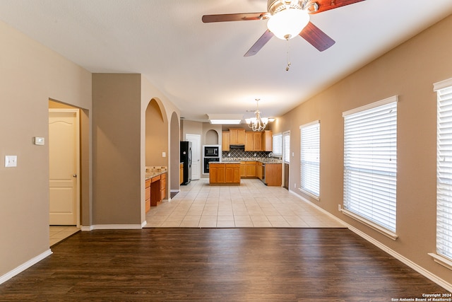 kitchen featuring stainless steel fridge, light hardwood / wood-style flooring, ceiling fan with notable chandelier, and oven