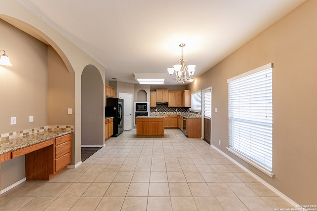 kitchen with tasteful backsplash, light stone countertops, black appliances, decorative light fixtures, and a chandelier