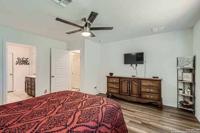 bedroom featuring a textured ceiling, connected bathroom, light wood-type flooring, and ceiling fan