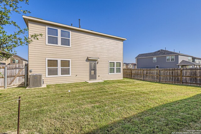 back of property with central air condition unit and a lawn