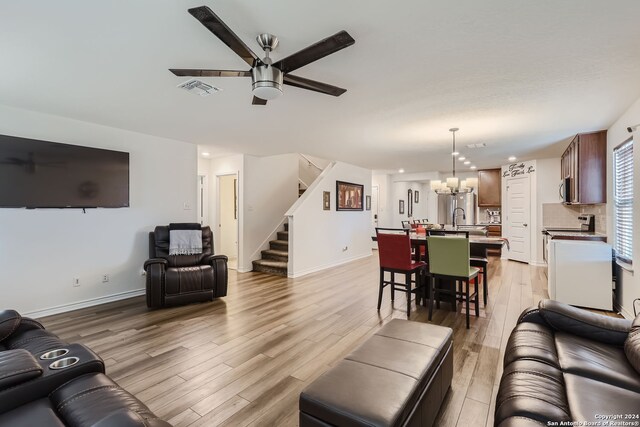 living room with sink, light hardwood / wood-style flooring, and ceiling fan with notable chandelier