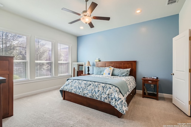 bedroom featuring light carpet, multiple windows, and ceiling fan