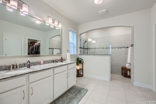 bathroom featuring vanity, a tile shower, and tile patterned flooring