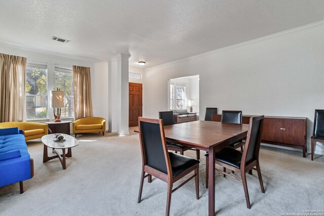 dining space featuring ornamental molding, ornate columns, a textured ceiling, and light colored carpet