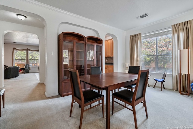 carpeted dining space with ornamental molding and a textured ceiling