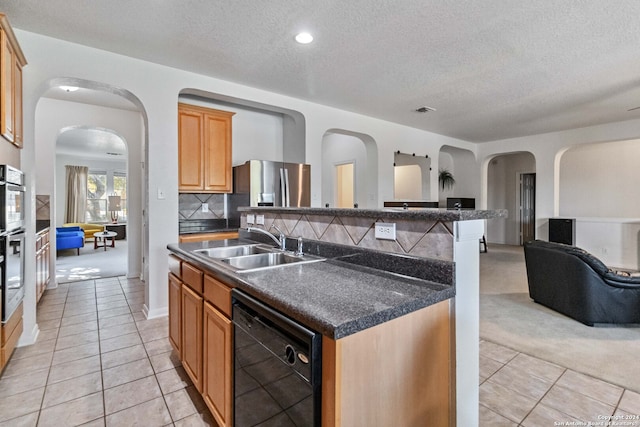 kitchen with tasteful backsplash, sink, dishwasher, an island with sink, and a textured ceiling