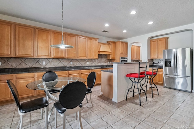 kitchen with a kitchen island, backsplash, hanging light fixtures, stainless steel appliances, and light tile patterned floors