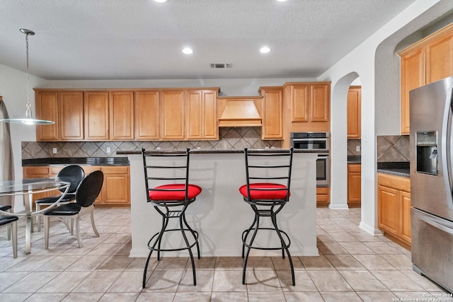 kitchen featuring premium range hood, stainless steel appliances, backsplash, and pendant lighting