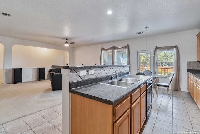 kitchen with a kitchen island with sink, sink, decorative light fixtures, light colored carpet, and a textured ceiling