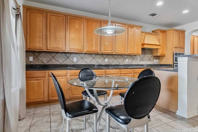 kitchen featuring premium range hood, decorative backsplash, light tile patterned floors, and pendant lighting