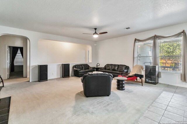 living room with a textured ceiling, carpet flooring, and ceiling fan