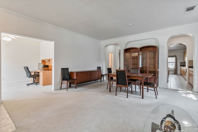 dining area featuring ornamental molding, a textured ceiling, light colored carpet, and ceiling fan