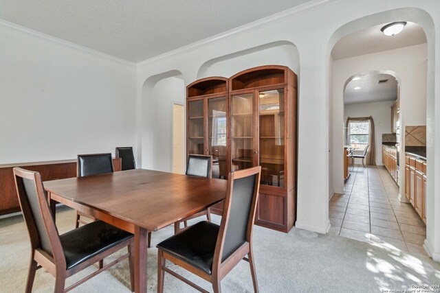 dining space featuring ornamental molding and light tile patterned floors