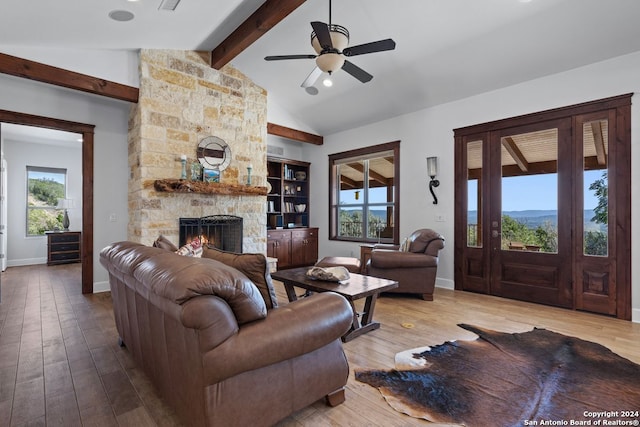 living room with a healthy amount of sunlight, wood-type flooring, vaulted ceiling with beams, and a fireplace