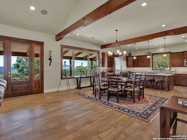 dining room with a wealth of natural light, a notable chandelier, vaulted ceiling with beams, and light wood-type flooring