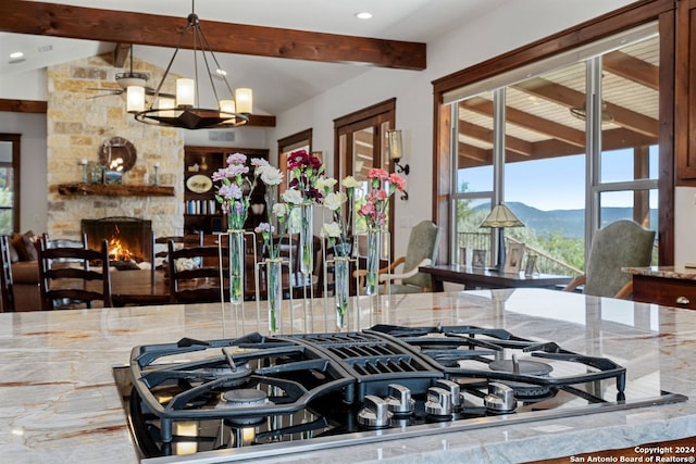 kitchen featuring gas cooktop, a stone fireplace, hanging light fixtures, a mountain view, and an inviting chandelier