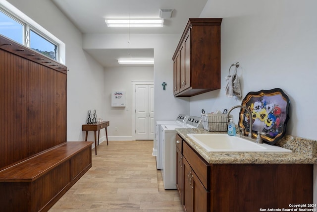 laundry room with light hardwood / wood-style floors, washer and dryer, sink, and cabinets