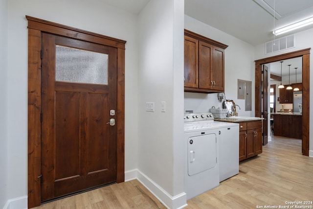 laundry room featuring cabinets, sink, washer and clothes dryer, and light hardwood / wood-style floors