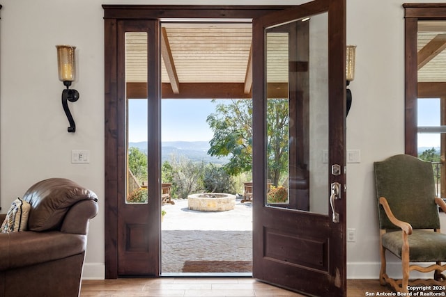 entryway featuring a mountain view, beam ceiling, and light wood-type flooring