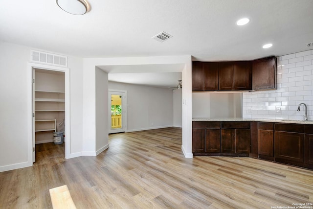 kitchen with light hardwood / wood-style floors, dark brown cabinets, sink, and backsplash