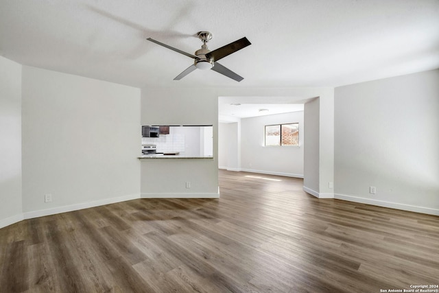 unfurnished living room featuring ceiling fan and dark hardwood / wood-style flooring