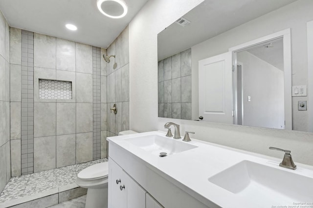 bathroom with vanity, a tile shower, and toilet