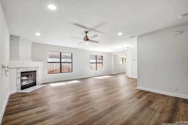 unfurnished living room featuring a tiled fireplace, ceiling fan, and dark hardwood / wood-style flooring