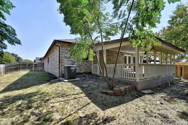 back of house with cooling unit and a lawn