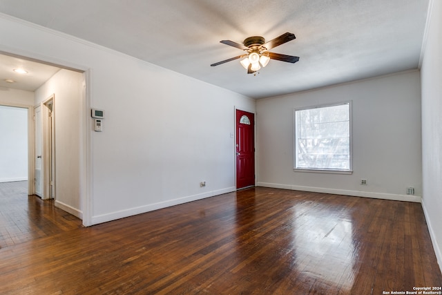 empty room with ornamental molding, dark wood-type flooring, and ceiling fan