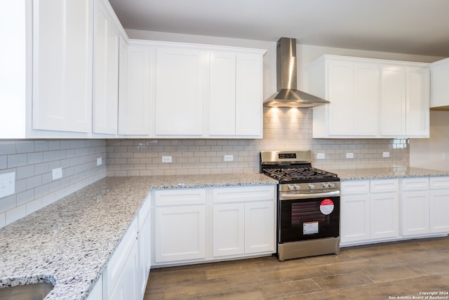 kitchen featuring wall chimney range hood, white cabinetry, light hardwood / wood-style floors, and stainless steel gas range