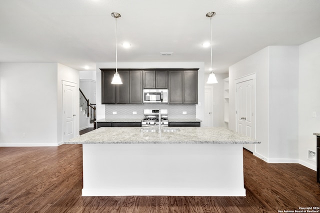 kitchen featuring a center island with sink, appliances with stainless steel finishes, pendant lighting, and dark hardwood / wood-style floors