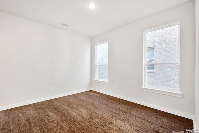 spare room featuring a wealth of natural light and dark hardwood / wood-style floors