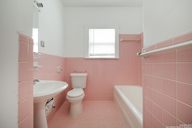 bathroom featuring a bath, toilet, and tile walls