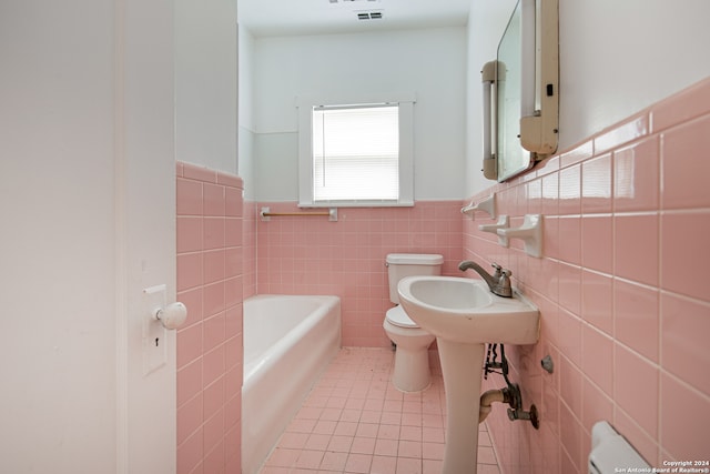 bathroom featuring a tub to relax in, tile walls, toilet, and tile patterned floors