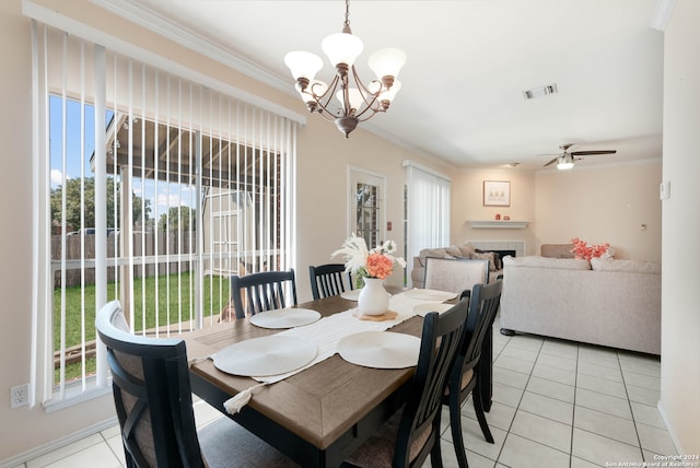 tiled dining area featuring ornamental molding, ceiling fan with notable chandelier, a fireplace, and a wealth of natural light