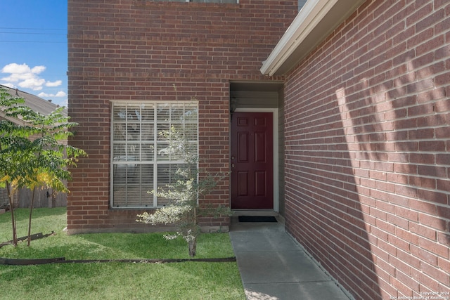 view of exterior entry with a lawn