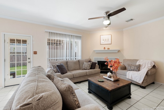 tiled living room with a tiled fireplace, crown molding, and ceiling fan