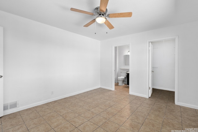 unfurnished bedroom with a walk in closet, light tile patterned floors, ceiling fan, ensuite bathroom, and a closet