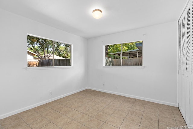 unfurnished bedroom with a closet, light tile patterned floors, and multiple windows