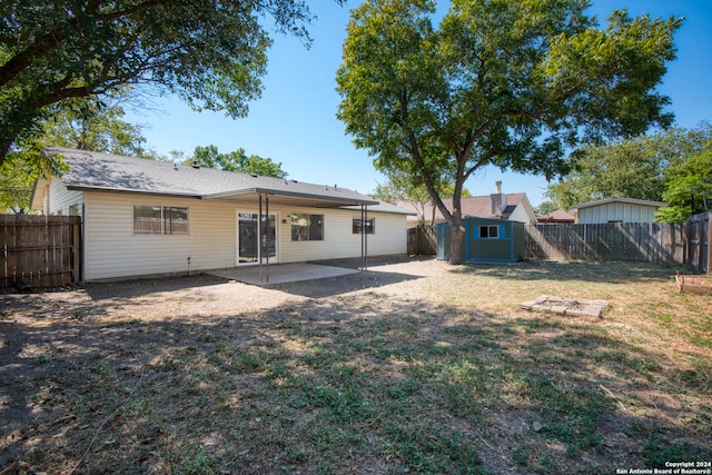 back of property featuring a patio, a storage shed, and a yard