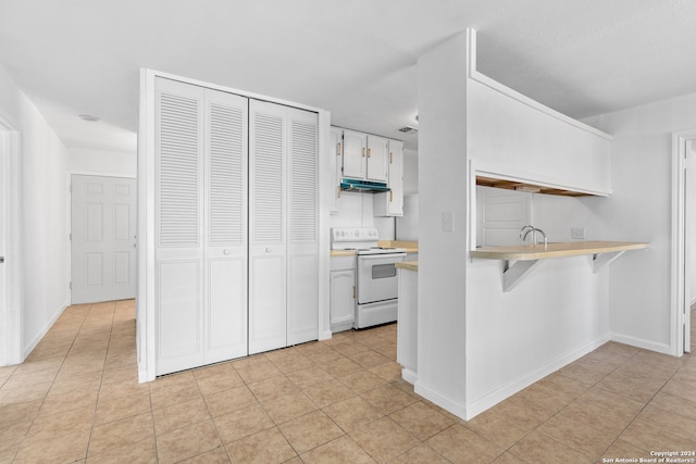 kitchen featuring a kitchen bar, kitchen peninsula, white cabinets, white electric range, and light tile patterned floors