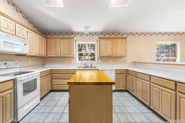 kitchen featuring a healthy amount of sunlight, a kitchen island, butcher block counters, and white appliances