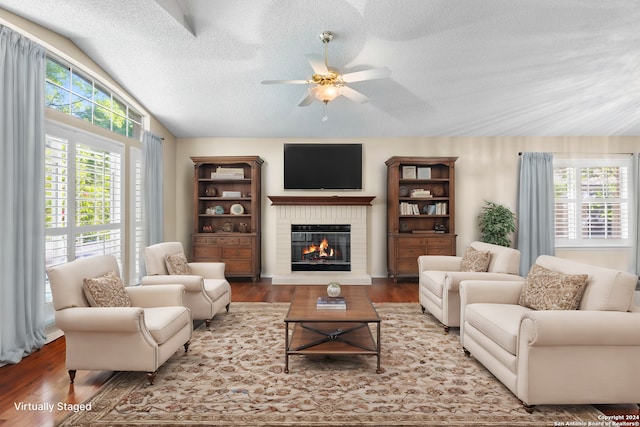 living room with a textured ceiling, hardwood / wood-style flooring, a fireplace, and vaulted ceiling